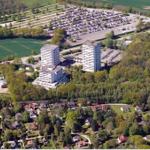 Luftbild von Wohngebieten, Hochhäusern und grünen Flächen mit Parkplatz.