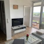 Wohnzimmer mit TV, Tisch und Balkonblick.