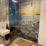 Duschbereich mit Meeresmotiv-Wand und Badezimmermöbeln
