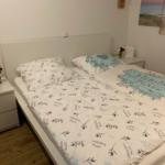 Schlafzimmer mit Bett, Nachttischen und Strandbild an der Wand.