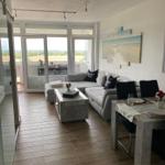 Wohn- und Essbereich mit Sofa, Tisch und Blick auf Balkon.