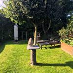 Garten mit Liegen, Baum, Grill und Gemüsebeet.