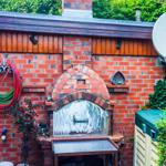 Außenbereich mit Backofen, Schlauch und Satellitenschüssel an Backsteinwand