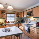 Küche mit Holzschränken, Arbeitsplatte und Fenster zum Außenbereich.