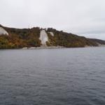 Weitläufiger Blick auf Küstenlandschaft mit weißen Felsen und farbenfrohem Herbstwald.
