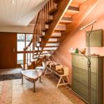 Eingangsbereich mit Holztreppe, Schrank und Tisch. Spielzeugregal und Stehlampe sind sichtbar.