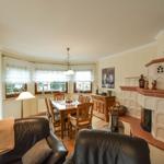 Wohn- und Essbereich mit Holztisch, Ledersofa und Kamin.