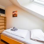 Schlafzimmer mit Dachschrägen, Bett, Fernseher und Bücherregal.