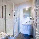 Badezimmer mit Dusche, Waschbecken und Heizkörper