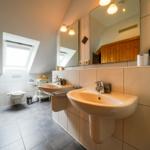 Badezimmer mit zwei Waschbecken, Spiegel und Dachfenster.