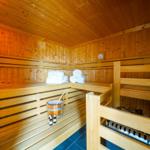 Sauna mit Holzbänken, Handtuchstapel und Holzschale.