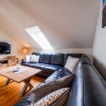 Wohnzimmer mit Sofa, Couchtisch und Fernseher unter Dachschräge