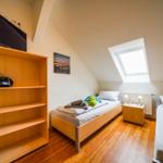 Zimmer mit zwei Betten, Dachschrägen, Dachfenster und Holzboden.