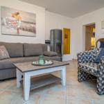 Wohnzimmer mit Sofa, Sessel und Kaminofen. Wandbild und Holztisch.