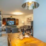 Essbereich mit Holztisch und Sitzgelegenheiten im Wohnzimmer mit Fernseher und Kamin.