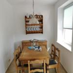 Esszimmer mit Holztisch, Stühlen und Wandregal mit Geschirr.