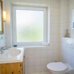 Badezimmer mit Waschbecken, Toilette und Fenster mit getöntem Glas.