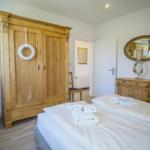 Schlafzimmer mit Bett, Holzschrank und Spiegelschrank.