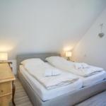 Schlafzimmer mit Doppelbett, Nachttischen und Fenster.