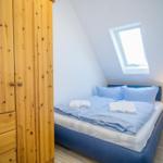 Schlafzimmer mit Dachschrägen, Holzschrank und Dachfenster.