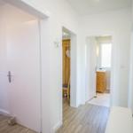 Flur mit Türen zu Schlafzimmer und Bad, Holzboden und Spiegel an der Wand.