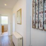 Flur mit Holzboden, Spiegel und Wanddekoration mit Haken.