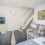 Wohn- und Essbereich mit Sofa, TV und Treppe.