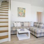 Wohnzimmer mit Ecksofa, Treppe und Wandbild.