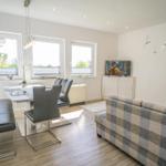 Wohn- und Essbereich mit Sofa, Esstisch und TV.