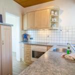 Küche mit Holzschränken, Granitplatte und Edelstahlspüle.