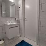 Badezimmer mit Waschbecken, Spiegel und blauem Teppich
