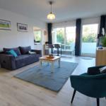 Wohnzimmer mit Sofa, Sessel und Balkon. Holzboden und Wandbilder.
