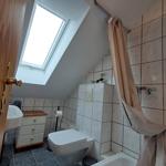 Badezimmer mit Dusche, Toilette und Waschbecken unter Dachschrägen.