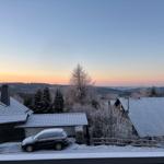 Schneebedeckte Dächer und Bäume bei Sonnenuntergang