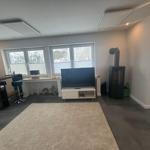 Wohnzimmer mit TV, Kaminofen und Fenster zur Aussicht.