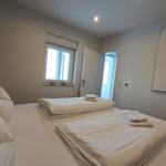 Zimmer mit Bett, Fenster und Tür. Bett mit Bettwäsche und Handtüchern.