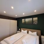 Schlafzimmer mit Bett, Nachttischen und Wandbildern.