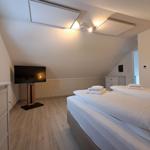 Schlafzimmer mit Doppelbett, TV und Schränken unter schrägem Dach