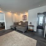 Wohnzimmer mit grauem Sofa, Teppich und Blick in Essbereich und Flur.