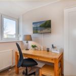 Arbeitszimmer mit Schreibtisch, Stuhl und Fernseher an der Wand.
