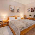 Schlafzimmer mit Holzbett, Nachttischen und Bildern an der Wand.