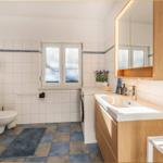 Badezimmer mit Waschmaschine, Spiegel und Toilette