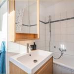 Badezimmer mit Badewanne, Dusche, Waschbecken und Spiegelschrank.