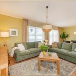 Wohnzimmer mit grünem Sofa, Holztisch und Fernseher.