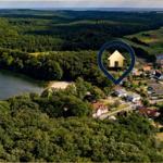 Liegenschaft am See mit Wald und Golfplatz im Hintergrund.