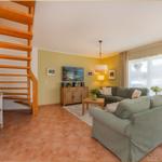 Wohnzimmer mit Sofa, Fernseher und Holztreppe.