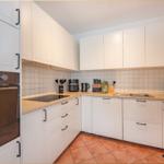 Küche mit weißen Schränken, Holzoberflächen und integriertem Backofen.
