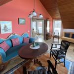 Wohnzimmer mit blauem Sofa, Holztisch und Sessel unter Holzdecke.