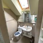 Badezimmer mit Dusche, Toilette und Waschbecken unter Dachschrägen.
