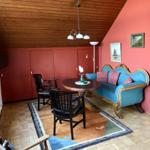 Wohnzimmer mit blauem Sofa, runden Tisch und Holzdecke.